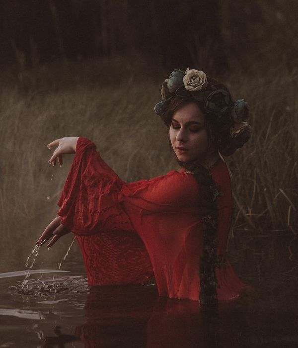 Woman in a calm, flowing pose against a dark background, embodying serenity.